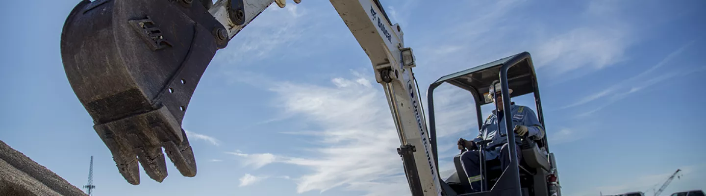 mini excavator on jobsite with extended bucket