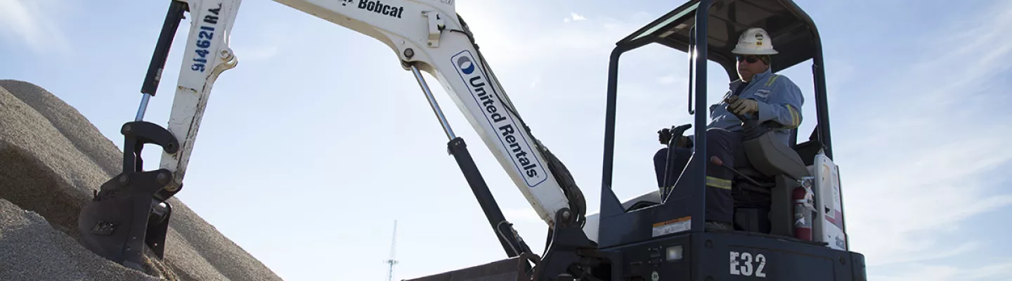 man in mini excavator near dirt pile