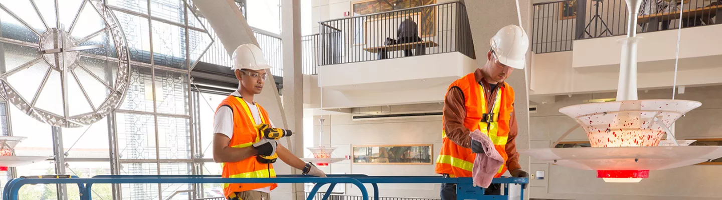 Two workers on a scissor lift inside of a building