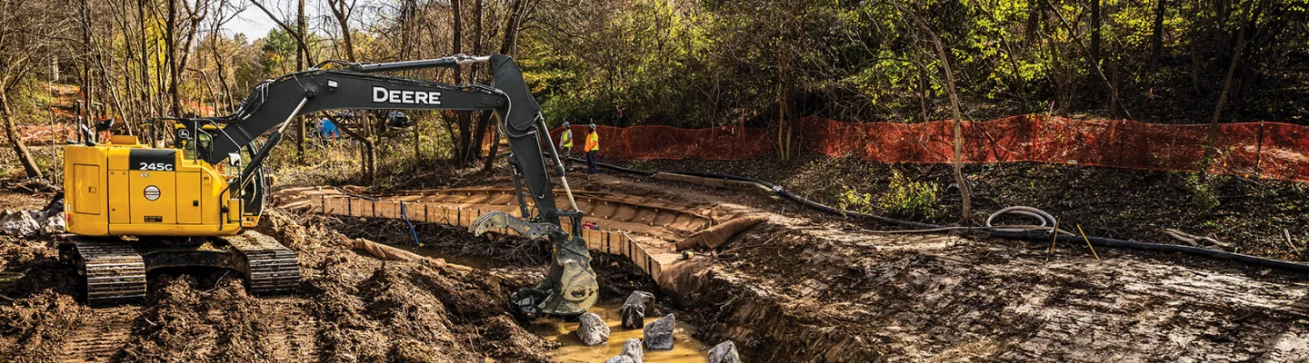 Yellow John Deere excavator digging in the dirt