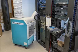 Light blue and white united rentals spot cooler in front of a server in a data center