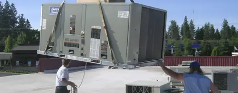 an air system being hosted in the air while two men move it into position outside