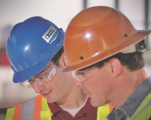 Two men in hard hats and safety vests talking