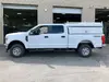 Side view of a white Chevrolet Silverado crew cab pickup truck with a white utility bed cap.