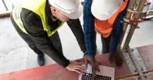 two civil engineers on construction site looking at laptop