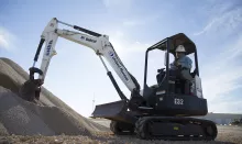 man in mini excavator near dirt pile