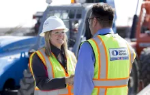 man shaking womans hand, both wearing PPE next to truck
