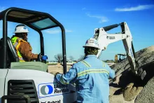 2 construction workers with mini excavator on jobsite