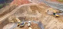 "Excavators assisting construction crews on-site, with safety barriers in place to control access and protect workers."







